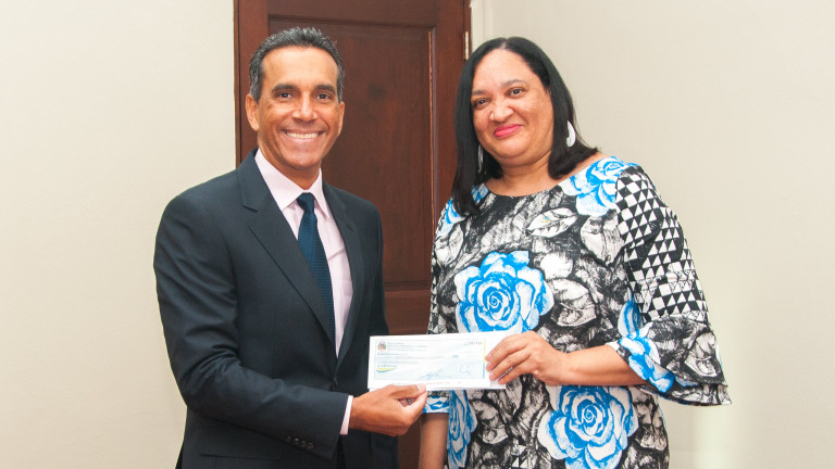 Viceministro de Producción y Desarrollo Comunitario del Ministerio Administrativo de la Presidencia, Juan Pumarol, entrega cheque a Yaquelín Almonte de Fernández, directora ejecutiva de INDENOR